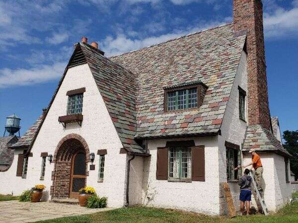 Color image of people working on the east-facing window of the Lodge House at the Packard Proving Grounds.